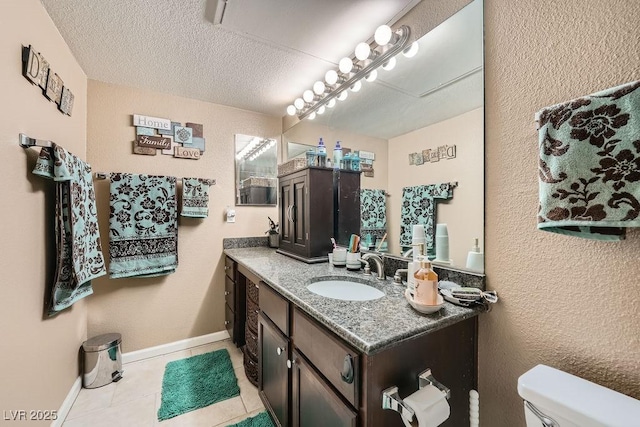 bathroom with tile patterned flooring, vanity, a textured ceiling, and toilet