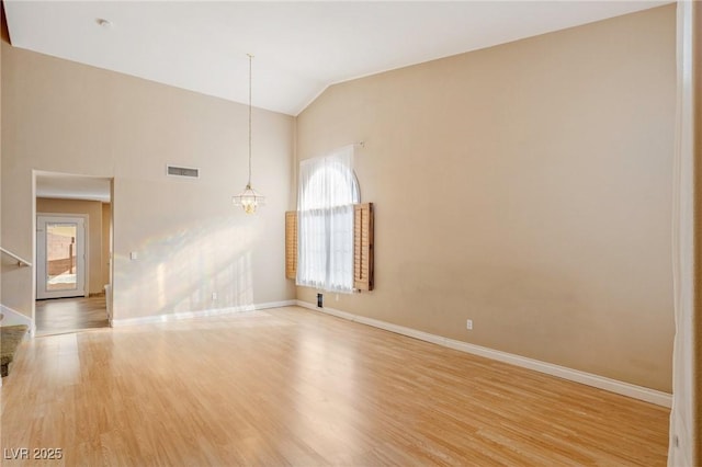 spare room featuring lofted ceiling, an inviting chandelier, and light hardwood / wood-style floors