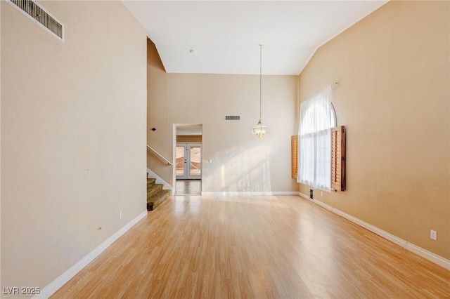 unfurnished living room featuring an inviting chandelier, wood-type flooring, and a high ceiling