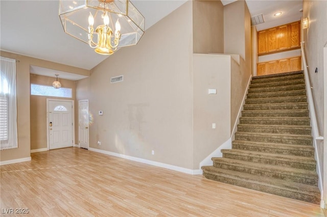 entrance foyer with an inviting chandelier, high vaulted ceiling, and light wood-type flooring