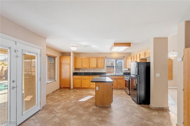 kitchen with a kitchen island, black refrigerator, decorative light fixtures, gas range, and light brown cabinets