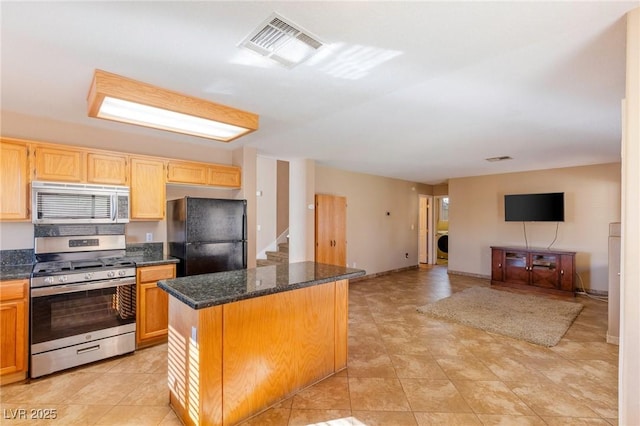 kitchen featuring washer / clothes dryer, appliances with stainless steel finishes, a center island, and dark stone counters