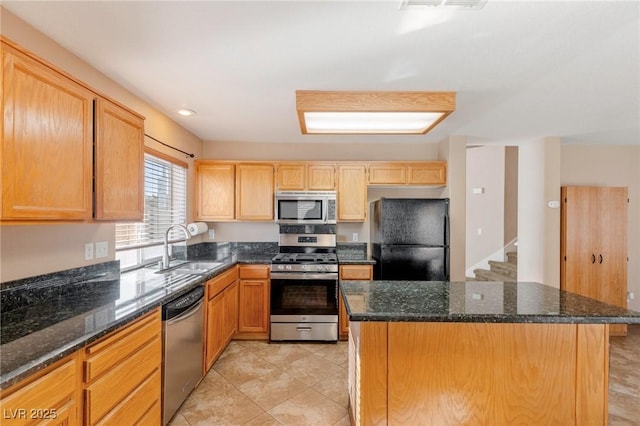 kitchen featuring stainless steel appliances, a center island, sink, and dark stone countertops