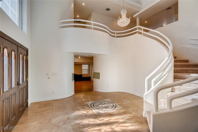 foyer entrance with an inviting chandelier, a towering ceiling, and light tile patterned flooring