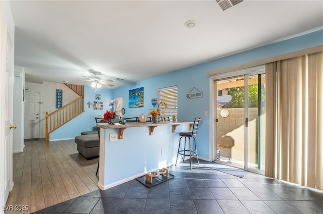 kitchen featuring kitchen peninsula, ceiling fan, and a kitchen bar