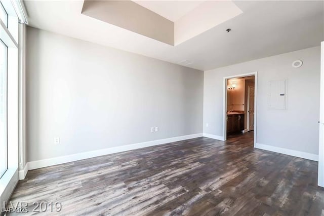 interior space featuring electric panel, dark hardwood / wood-style flooring, and a tray ceiling