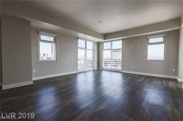 empty room with a healthy amount of sunlight and dark wood-type flooring