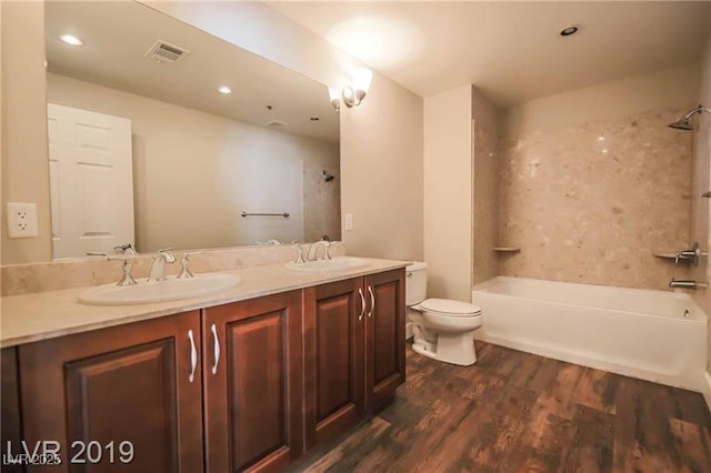 full bathroom with vanity, hardwood / wood-style flooring, tiled shower / bath combo, and toilet