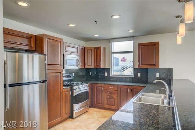 kitchen featuring sink, backsplash, hanging light fixtures, stainless steel appliances, and dark stone counters