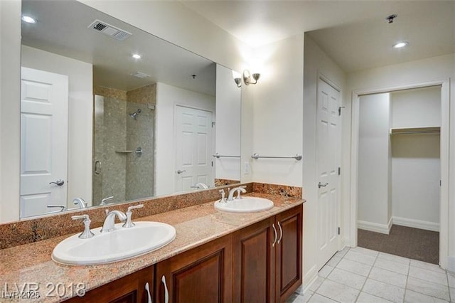 bathroom with walk in shower, vanity, and tile patterned flooring