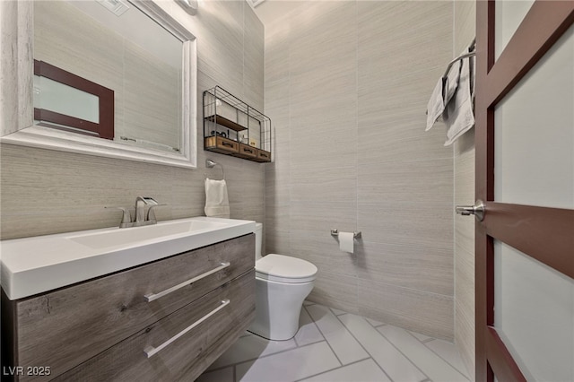 bathroom featuring tile patterned flooring, vanity, tile walls, and toilet