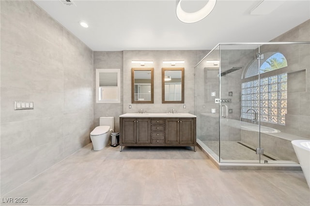 bathroom with tile walls, vanity, toilet, and walk in shower