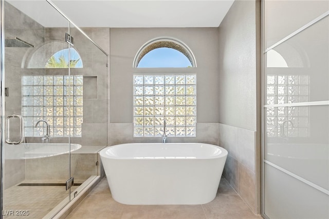 bathroom with plus walk in shower, tile patterned flooring, and tile walls