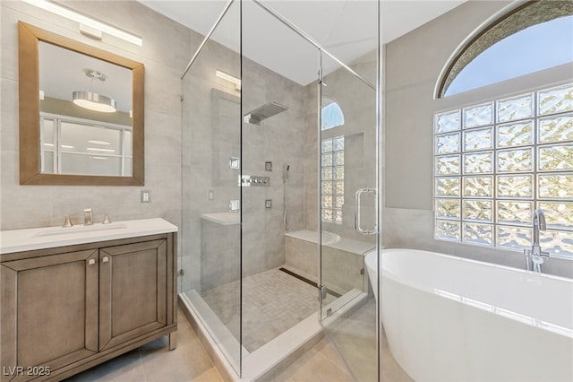 bathroom featuring tile patterned flooring, plus walk in shower, tile walls, and vanity