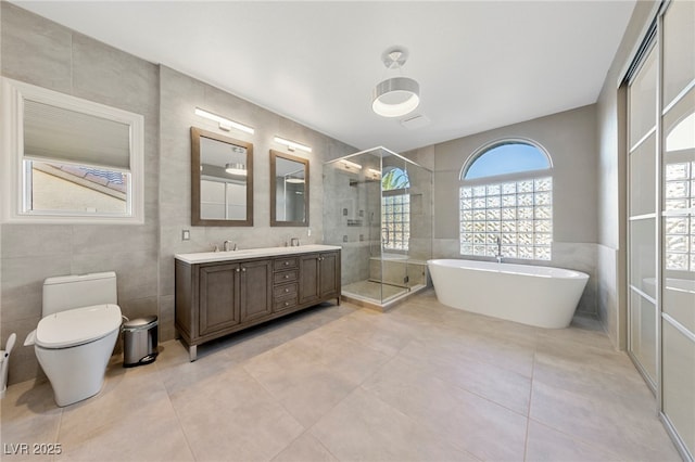 full bathroom featuring shower with separate bathtub, tile walls, vanity, toilet, and tile patterned floors