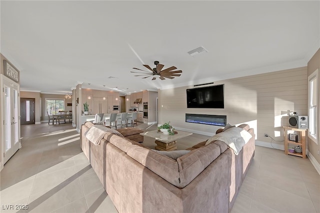 living room featuring crown molding, light tile patterned floors, and ceiling fan