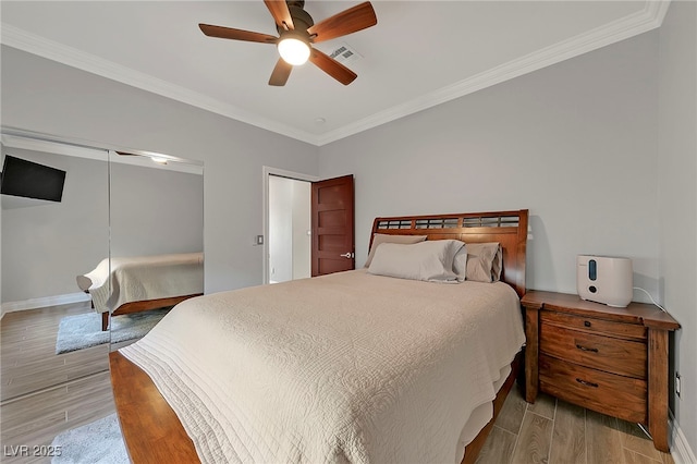 bedroom with crown molding, light hardwood / wood-style flooring, a closet, and ceiling fan