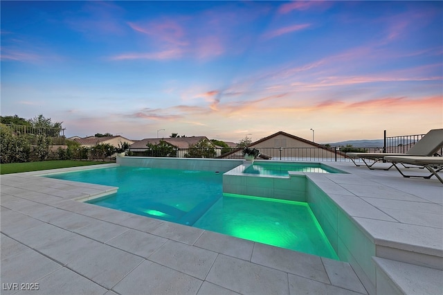 pool at dusk featuring a patio