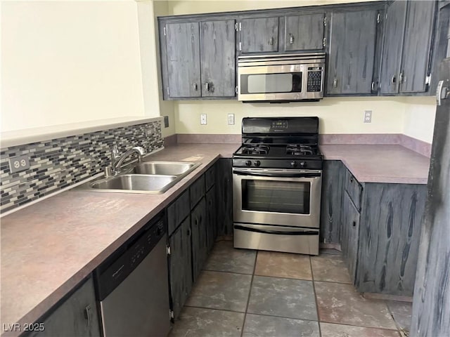 kitchen featuring sink, gray cabinetry, stainless steel appliances, tasteful backsplash, and dark tile patterned flooring