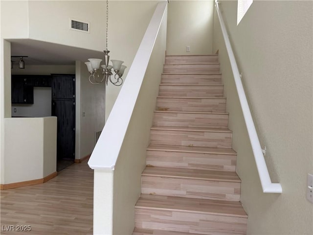 staircase with a chandelier and hardwood / wood-style floors