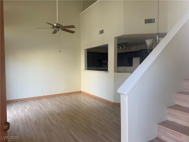 unfurnished living room with a high ceiling, wood-type flooring, and ceiling fan