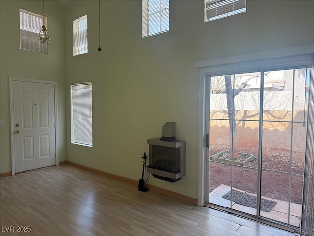 unfurnished living room featuring a high ceiling, wood-type flooring, and an inviting chandelier