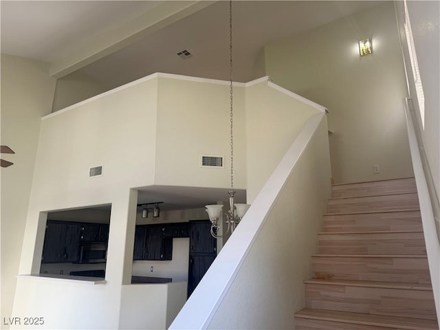 staircase featuring hardwood / wood-style flooring, a towering ceiling, and an inviting chandelier