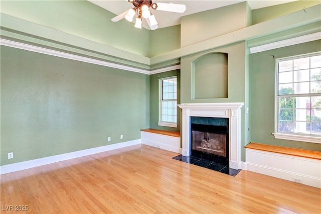 unfurnished living room featuring ceiling fan, wood-type flooring, and a fireplace