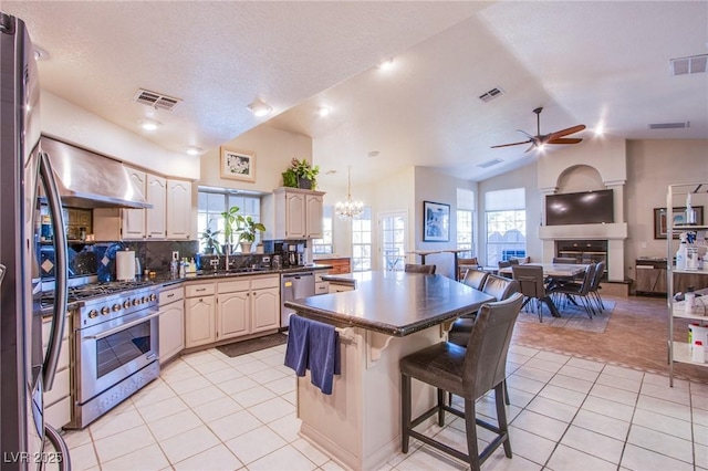 kitchen featuring lofted ceiling, stainless steel appliances, extractor fan, a kitchen bar, and light tile patterned flooring