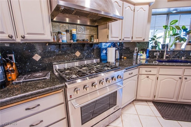 kitchen featuring high end stainless steel range, sink, backsplash, wall chimney range hood, and light tile patterned flooring