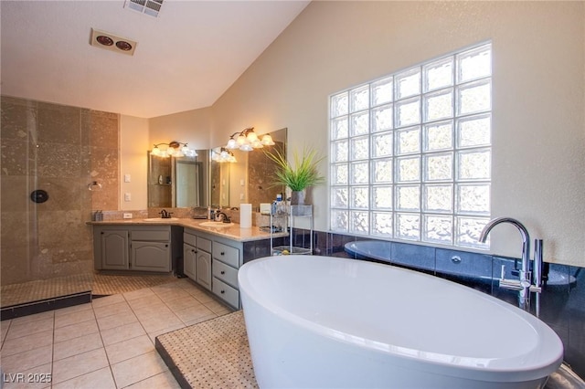 bathroom with vanity, tile patterned flooring, and a tile shower