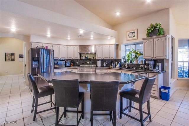 kitchen featuring appliances with stainless steel finishes, a kitchen island, wall chimney exhaust hood, and a breakfast bar