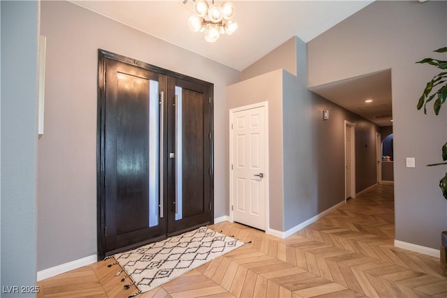 entrance foyer featuring arched walkways, vaulted ceiling, baseboards, and an inviting chandelier