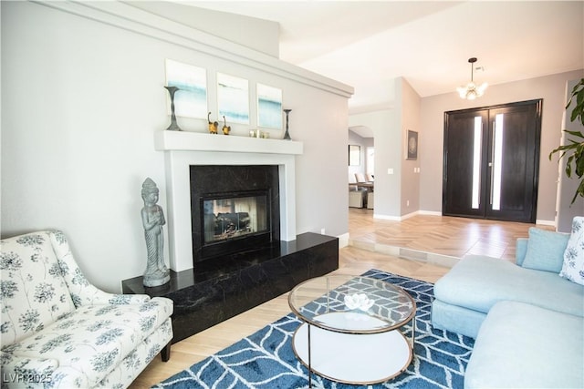 living area with arched walkways, a fireplace, a notable chandelier, and baseboards