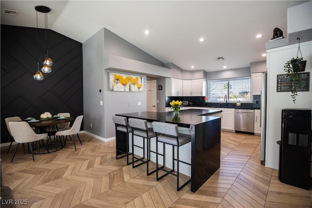 kitchen with dark countertops, visible vents, vaulted ceiling, and stainless steel dishwasher