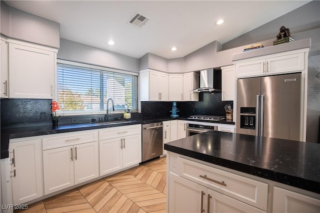 kitchen featuring stainless steel appliances, a sink, visible vents, wall chimney range hood, and backsplash