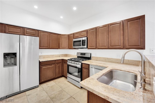 kitchen with sink, light tile patterned flooring, light stone countertops, and appliances with stainless steel finishes