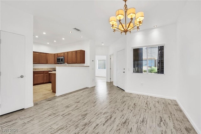 kitchen with a notable chandelier, light wood-type flooring, hanging light fixtures, and a wealth of natural light