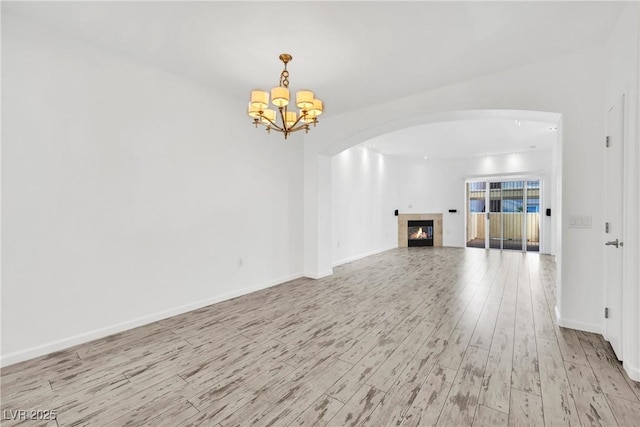 unfurnished living room with a notable chandelier, a fireplace, and light hardwood / wood-style floors