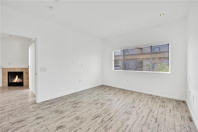 unfurnished room featuring a fireplace and light hardwood / wood-style flooring