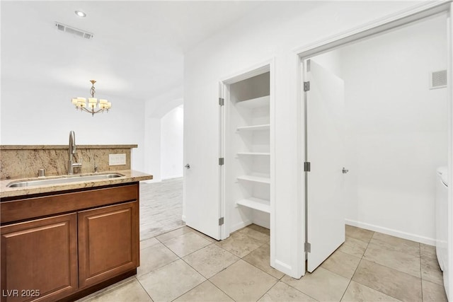 bathroom featuring tile patterned flooring, sink, backsplash, and a notable chandelier