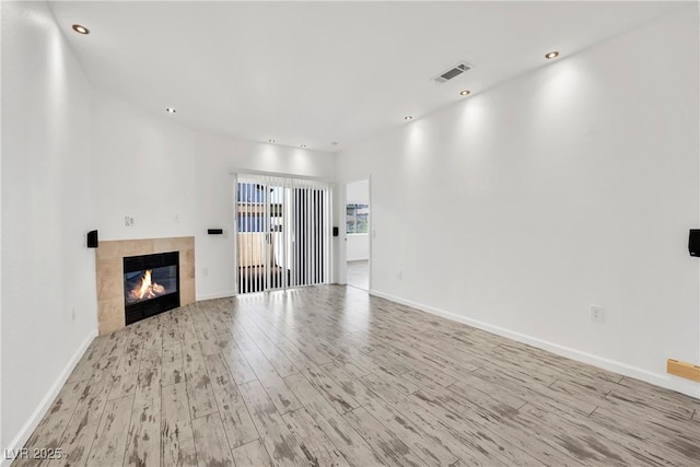 unfurnished living room featuring a tile fireplace and light wood-type flooring