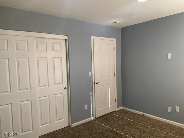 unfurnished bedroom featuring dark carpet and a closet