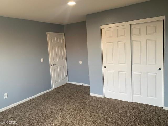 unfurnished bedroom featuring dark colored carpet and a closet