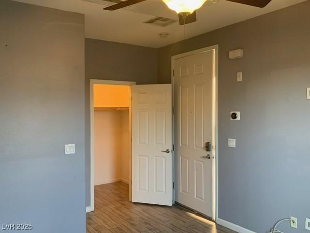 unfurnished bedroom with hardwood / wood-style flooring, ceiling fan, a spacious closet, and a closet