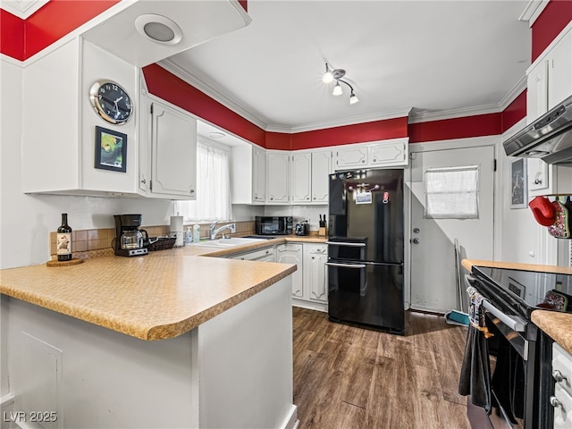 kitchen with dark wood-type flooring, sink, white cabinetry, black refrigerator, and kitchen peninsula