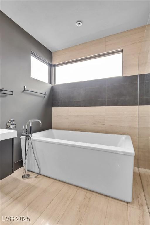 bathroom featuring a tub, hardwood / wood-style flooring, and a wealth of natural light