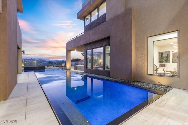 pool at dusk featuring a patio