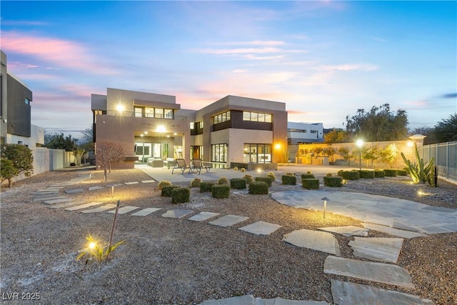 back house at dusk with a patio and a balcony