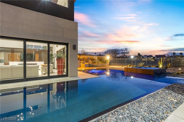 pool at dusk with a hot tub and a patio area